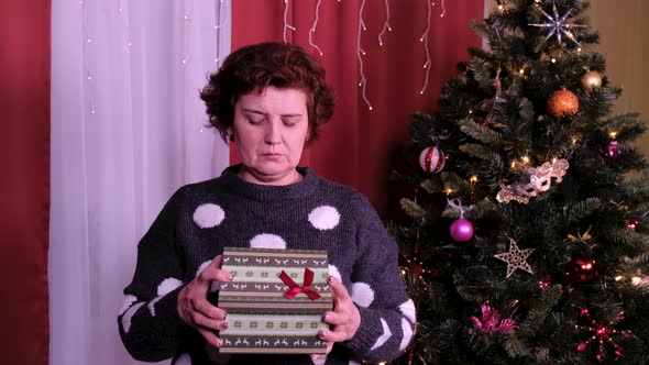 Woman Opens a Christmas Gift Package. Concept of Holidays and New Year. alt