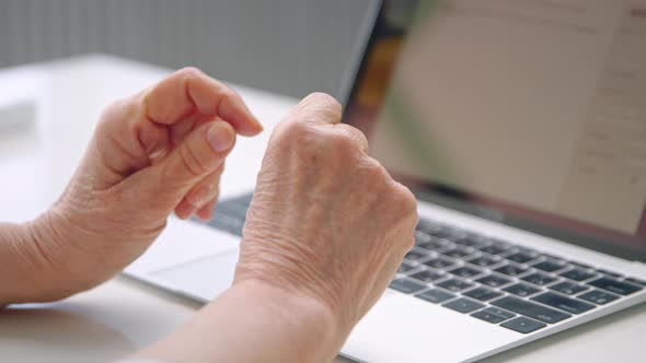 Old woman company manager holds wrinkly hands over keyboard alt