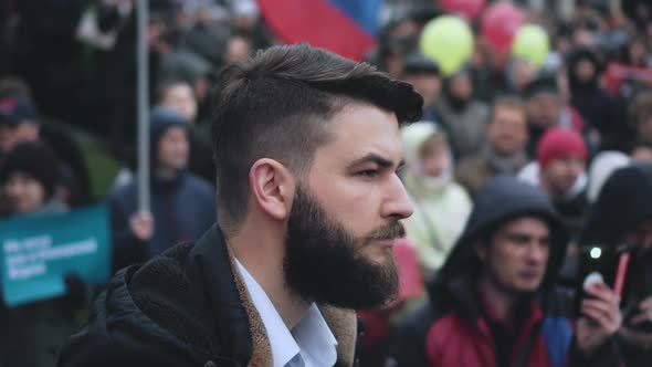 Portrait of Bearded Male Protester on Crowded City Street During Political Rally alt