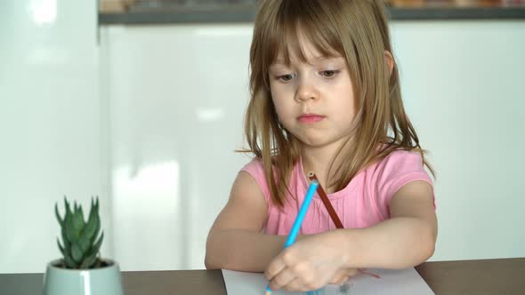 Portrait of Little Girl Draws with Pencils on Paper at Home