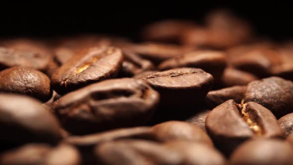 Close up view of fresh roasted coffee beans on black background in rotating motion