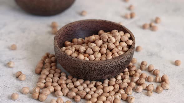 Pour Raw dry chickpea into a wooden bowl close up alt