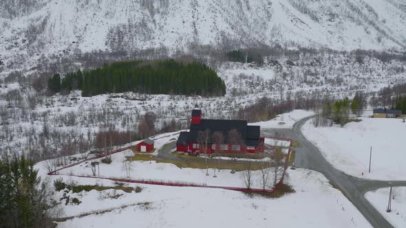 Slow aerial orbit around red Kåfjord wooden church, Olderdalen, Arctic alt