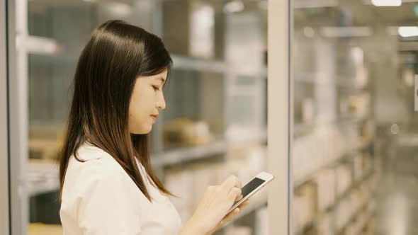 Female worker checking products with tablet in warehouse.