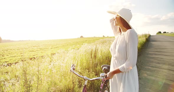 Woman Walking with Bicycle on Field Road