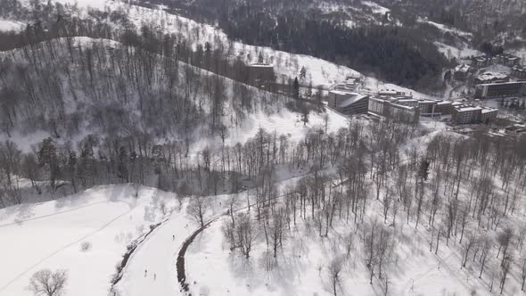 Aerial view of the ski resort with snowy mountain slopes and winter trees.  alt