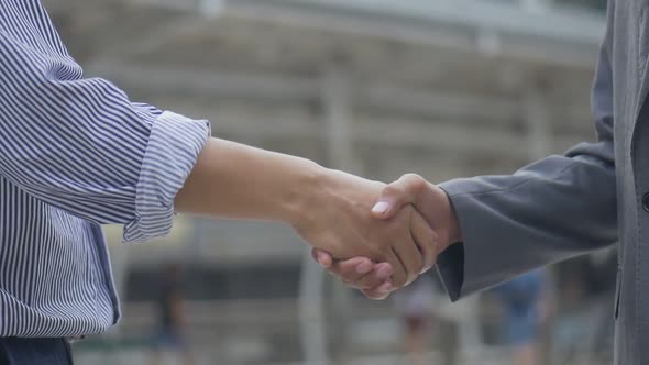 Asian businessman shaking hands with partners have success while standing in the urban city.