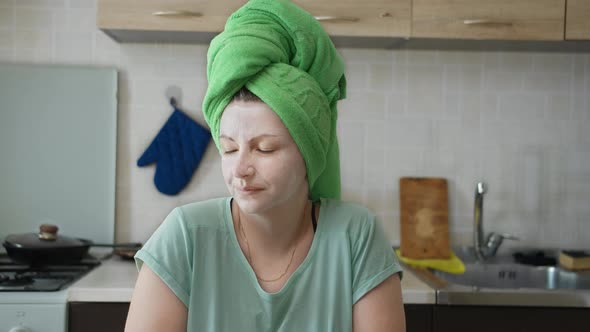 Portrait of Happy Pretty Woman with Towel on Head After Bath in Kitchen Thinking About Something