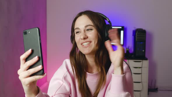 Young Smiling Woman in Headphones Talking to Boyfriend in Video Chat Using Smartphone alt