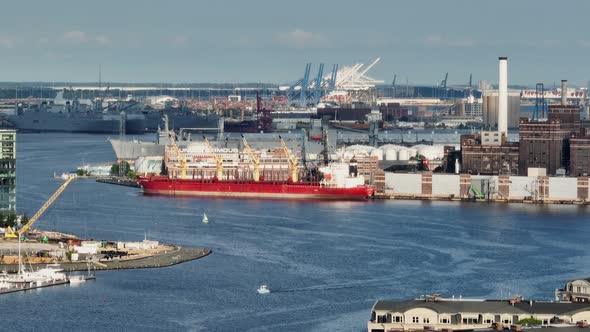 Cargo ships dock at port in USA. Long aerial zoom lens during golden hour light on hazy summer day. alt