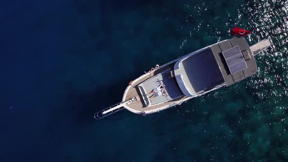 Top Drone View of Man and Woman Lying on the Deck of Yacht in the Blue Sea at Summer Day alt