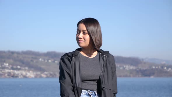 Southeast asian woman in front of European panorama, portrait shot. alt