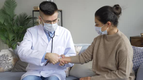 Positive male physiotherapist doctor checks the smiling young female patient lung's with stethoscope