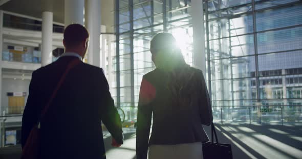 Businessman and businesswoman walking together in the lobby at office 4k alt