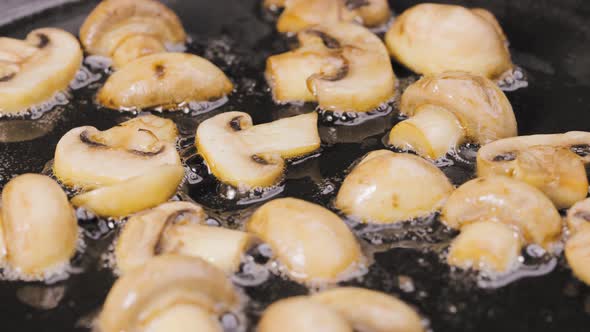 Golden Slices of Champignons are Fried Into a Hot Pan with Oilin Close Up alt
