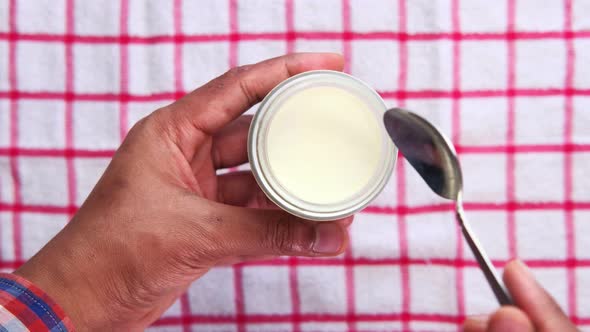 Top View of Man's Hand Eating Fresh Yogurt From a Bowl  alt