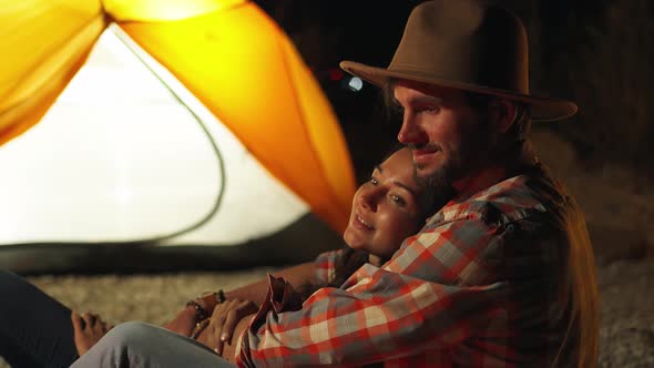 Man Hugging Woman in Front of the Bonfire on Beach Party in the Dark alt