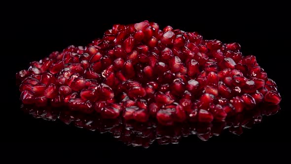 Heap of pomegranate grains. Red seeds of grenade rotating on a black background.