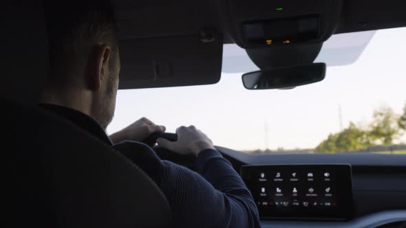 A Middleaged Handsome Caucasian Man Drives a Car on a Road  Rear Closeup From the Backseat