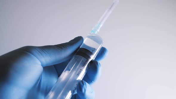 Hand in Blue Glove Holding Syringe alt