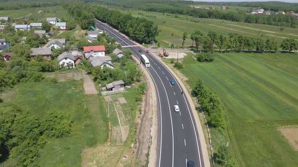 Aerial View of Intercity Road Between Green Agricultural Fields with Fast Driving Cars alt