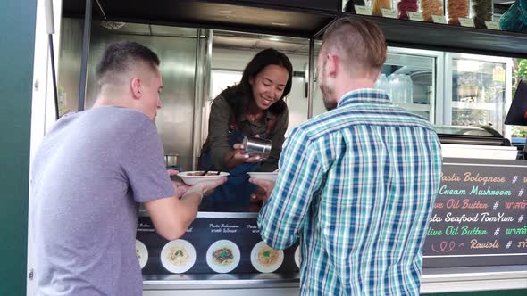 Young woman food truck owner with customers at the counter