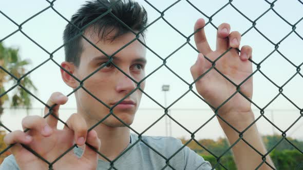Depressed Teenager Looks Over the Fence Mesh alt