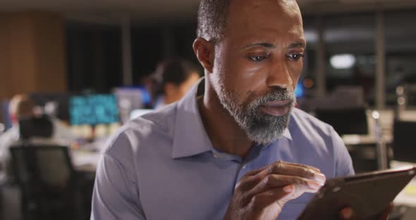 Thoughtful professional businessman using a digital tablet in modern office in slow motion alt