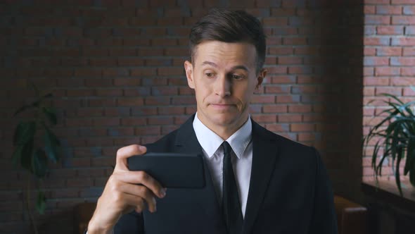 Young Man is Watching an Unpleasant Video on a Smartphone