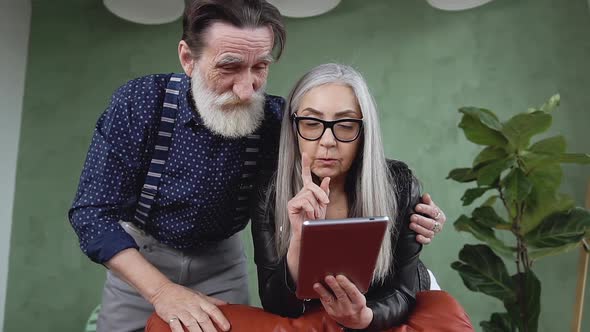 Stylish Mature Couple which Discussing Over i-pad Interesting Internet Apps alt