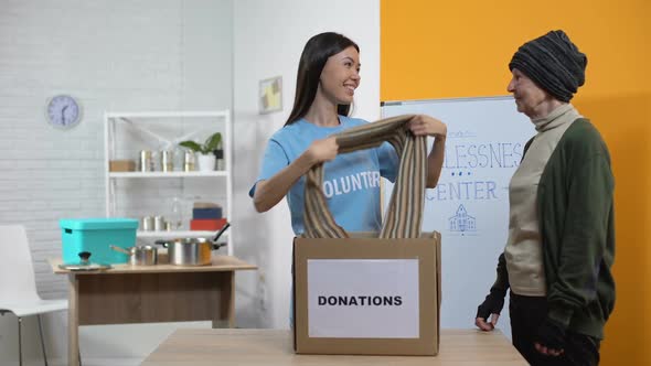 Female Volunteer Giving Scarf Poor Woman From Donation Box, Homeless Center alt