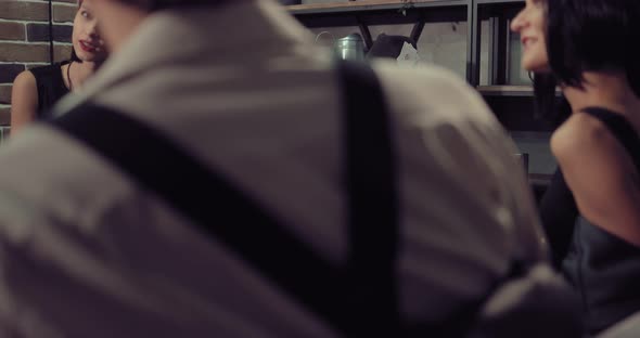 Rich Men with Beautiful Women are Sitting at a Poker Game Table Drinking Whiskey and Talking alt