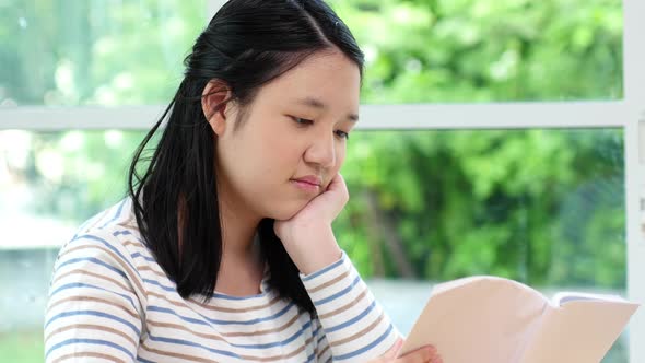 Asian Girl Reading A Book In Living Room alt