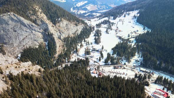 Aerial drone view of the spring Carpathians, Romania. Rocky slopes and valley with village, forest p alt