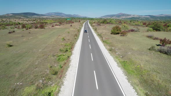 Aerial View Empty Asphalt Road on the Plateau Between Green Fields Highland Way alt