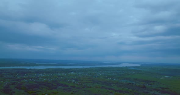 Aerial View of Small Village in Dusk or Dawn Gloomy Clouds Above River and Countryside  Prores
