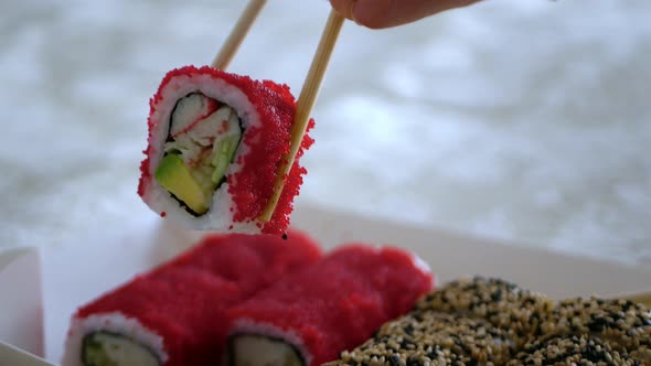 The Girl's Hand Takes Colorful Sushi and Dips It in Soy Sauce