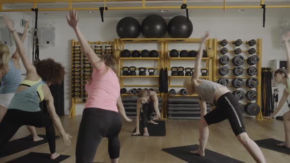 Group of adult women doing yoga exercises in gym