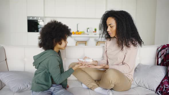 Young Mother and Her Son Treat Their Hands with an Antiseptic Spray to Prevent Covid19 alt