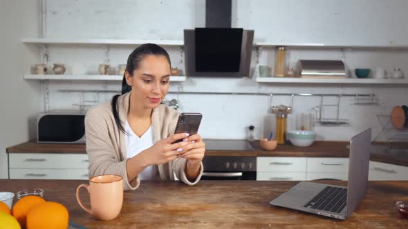 Housewife Checks Social Network While Sitting in the Kitchen alt