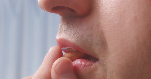 A Person Puts a Capsule in His Mouth alt