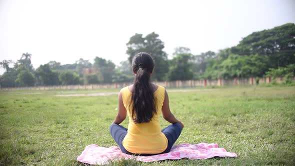 Young Asian girl doing meditation and Indian pranayam yoga showing back at morning sunrise alt