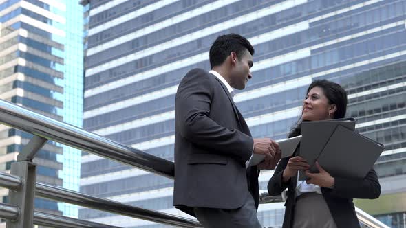 Indian businesswoman and businessman coworker talking friendly outside the office building