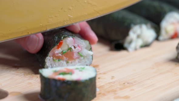 The Chef Cuts Sushi and Rolls Made From Seafood with Asian Ingredients with a Knife alt