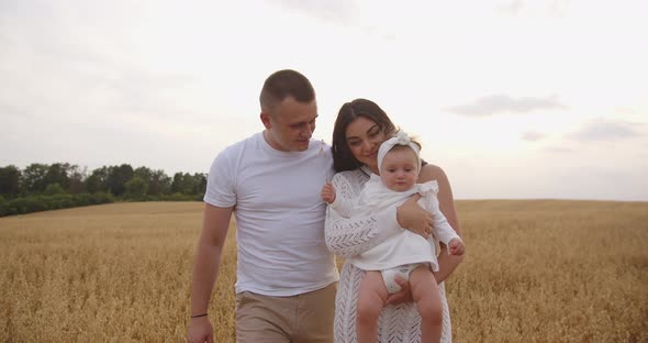 Loving Parents With A Baby Are Walking In The Field