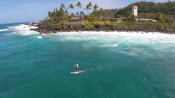 Aerial view of a man paddling while sup stand-up paddleboard surfing in Hawaii alt