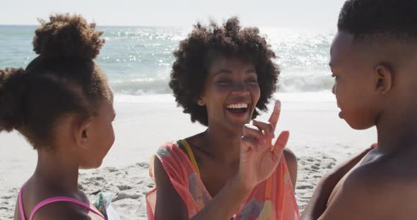 Smiling african american family using sun cream on sunny beach alt