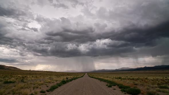 Timelapse of rainstorm looking down dirt road of into the desert landscape alt