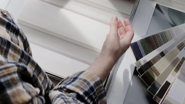 Woman fliping through catalog with roller blinds or window shade. alt