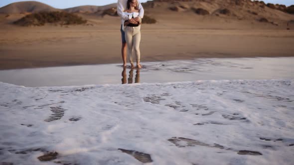 Bonding Young Couple Standing on Sandy Beach Shoreline Watch Sunset Waves From the Ocean alt
